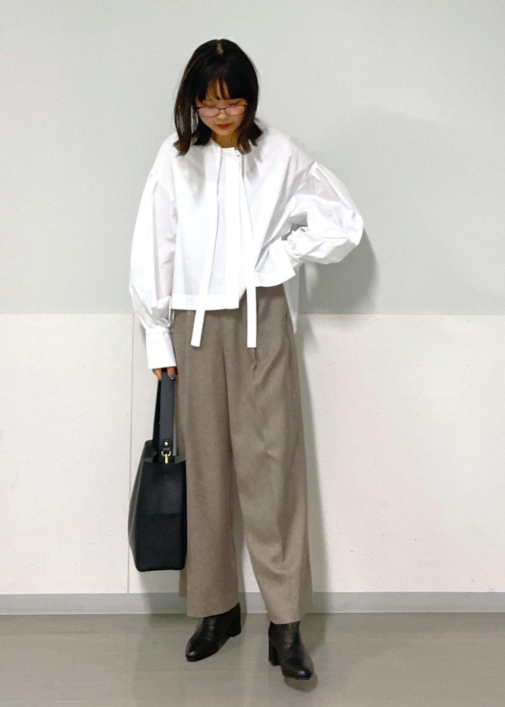 ベージュ系のスラックス、ベージュ系のジャンパースカート、ホワイト系のシャツ/ブラウスを着用したレディースの秋コーディネートの5枚目の写真