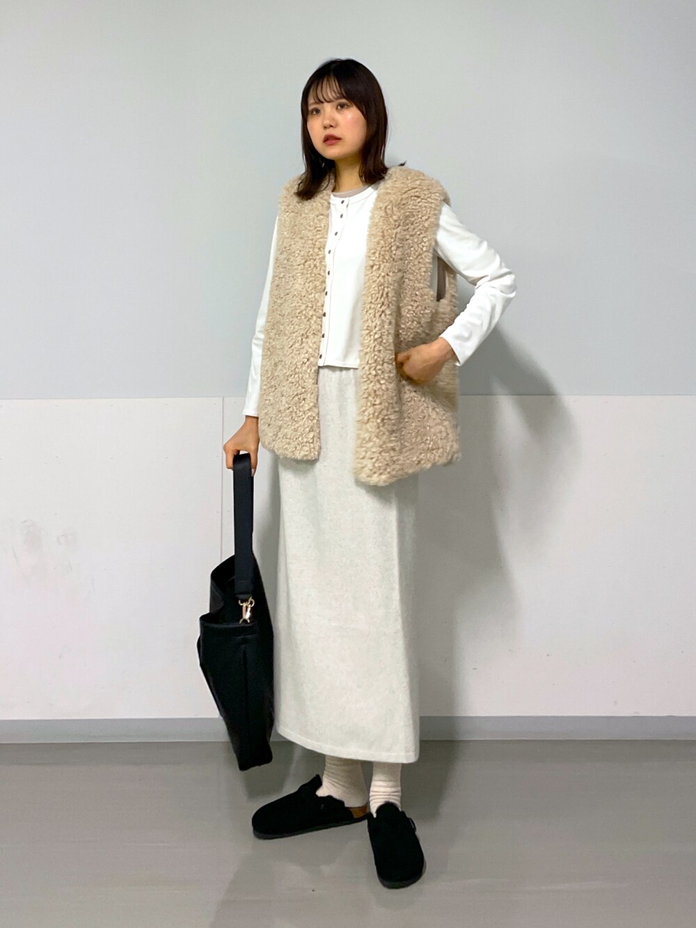 ホワイト系のカーディガン/ボレロ、ベージュ系のベスト、ホワイト系のスカートを着用したレディースの冬コーディネートの2枚目の写真