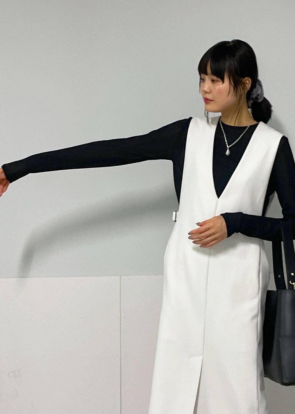 ブラック系のトートバッグ、ブラック系のTシャツ/カットソー、ホワイト系のジャンパースカートを着用したレディースの秋コーディネートの7枚目の写真