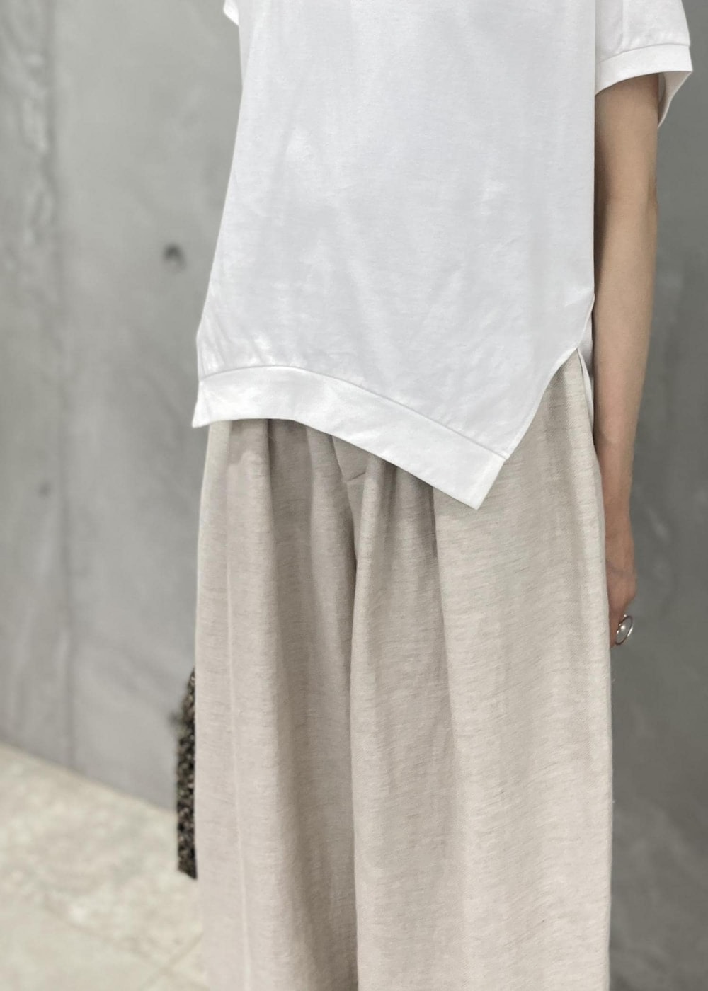 ブラック系のサンダル、ホワイト系のスラックス、ブラック系のハンドバッグを着用したレディースの春コーディネートの4枚目の写真