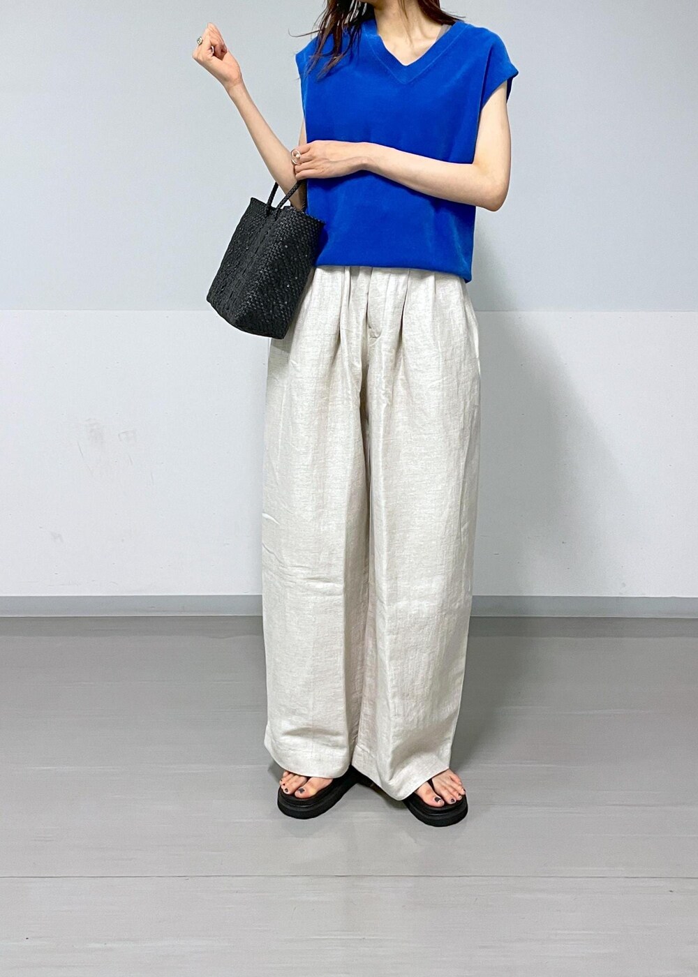 ブラック系のかごバッグ、ホワイト系のスラックス、ホワイト系のテーラードジャケットを着用したレディースの春コーディネートの6枚目の写真