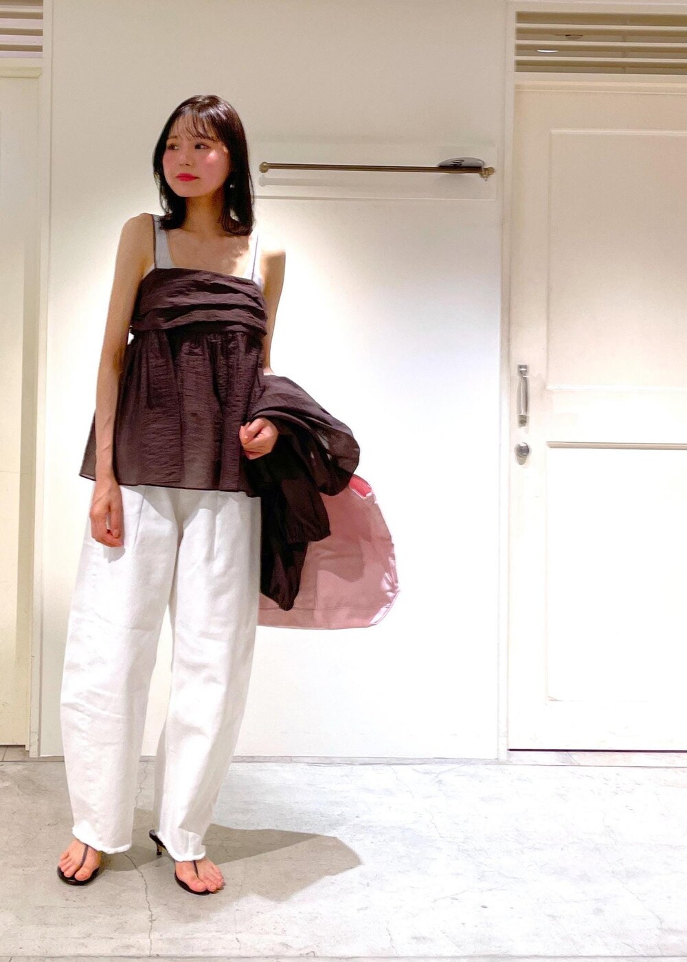 グレー系のタンクトップ、ブラック系のサンダル、ホワイト系のデニムパンツを着用したレディースの夏コーディネートの10枚目の写真