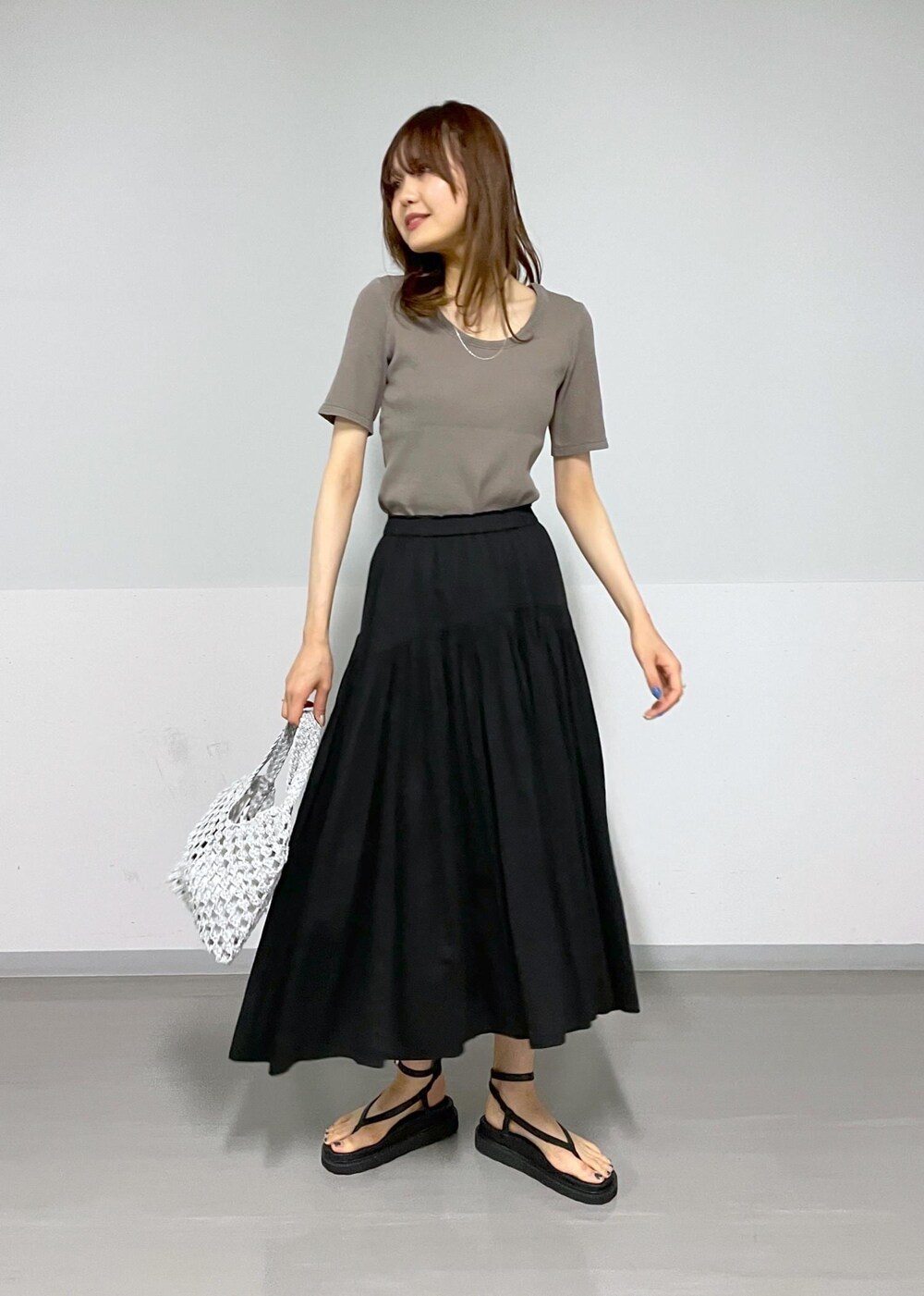 ブラック系のサンダル、ブラック系のスカート、グレー系のTシャツ/カットソーを着用したレディースの春コーディネートの2枚目の写真