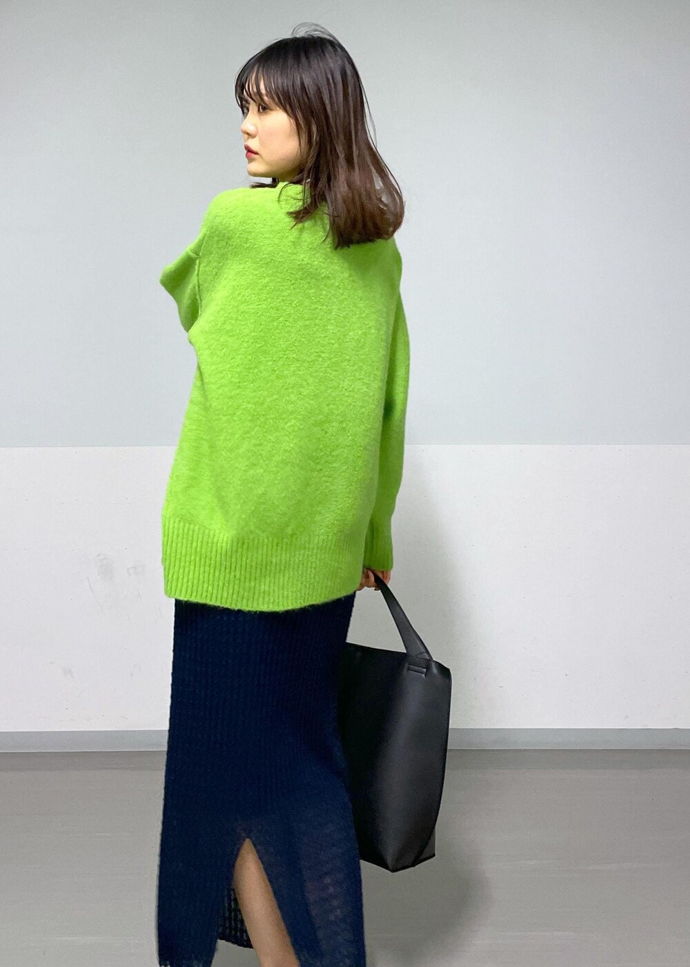 グリーン系のニット/セーター、ホワイト系のTシャツ/カットソー、ブラック系のトートバッグを着用したレディースの冬コーディネートの4枚目の写真