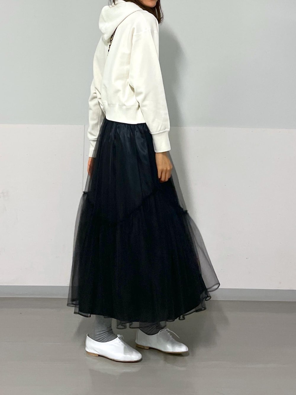 ブラック系のショルダーバッグ、ホワイト系のニット/セーター、ブラック系のスカートを着用したレディースの冬コーディネートの6枚目の写真