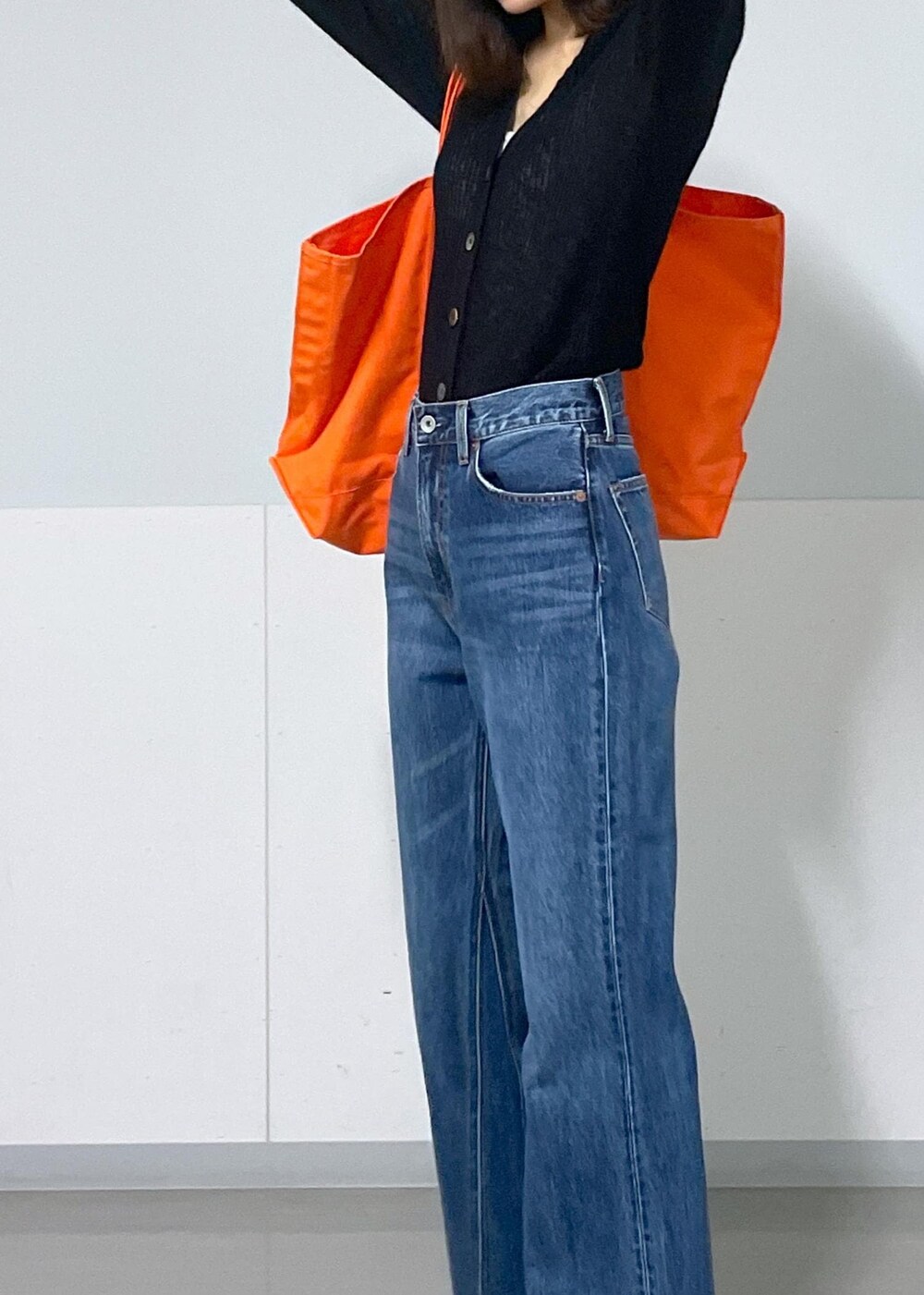 グレー系のタンクトップ、ブラック系のカーディガン/ボレロ、ブルー系のデニムパンツを着用したレディースの秋コーディネートの9枚目の写真