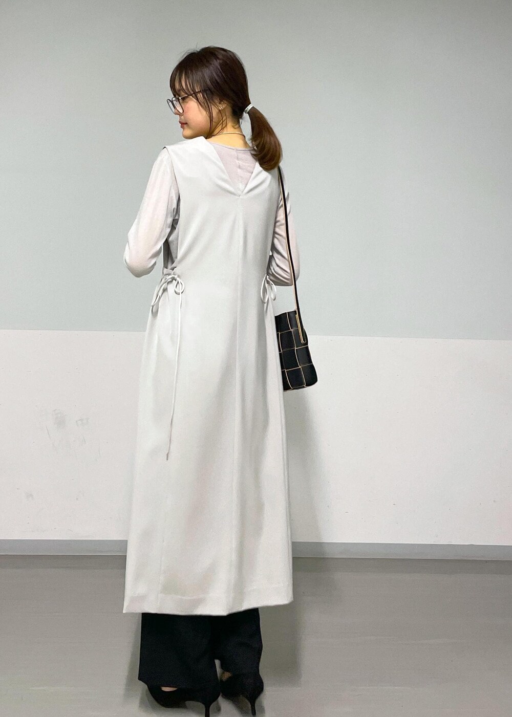 ベージュ系のジャンパースカート、グレー系のTシャツ/カットソー、ブラック系のスラックスを着用したレディースの春コーディネートの4枚目の写真