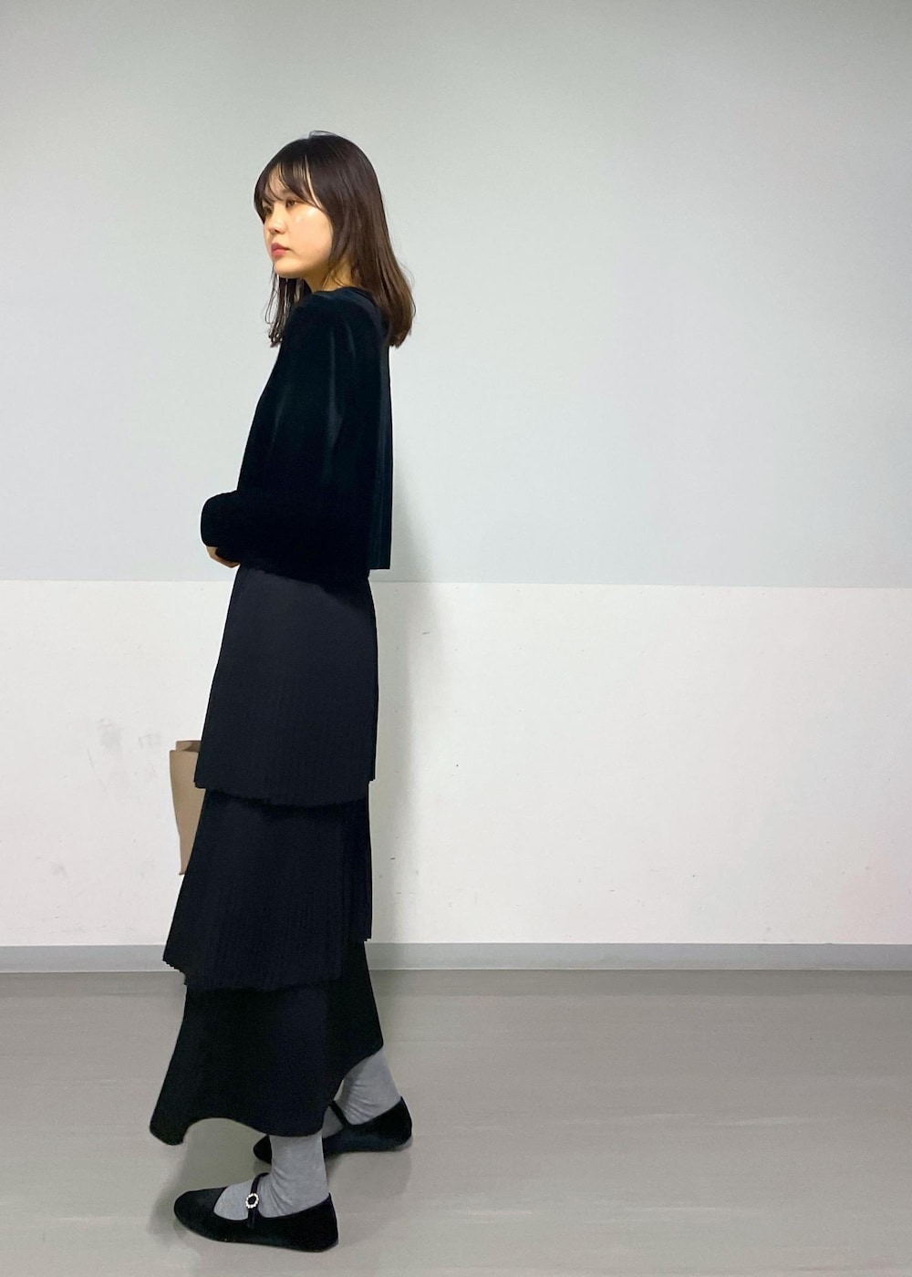 ブラック系のカーディガン/ボレロ、ブラック系のスカート、ベージュ系のハンドバッグを着用したレディースの冬コーディネートの6枚目の写真