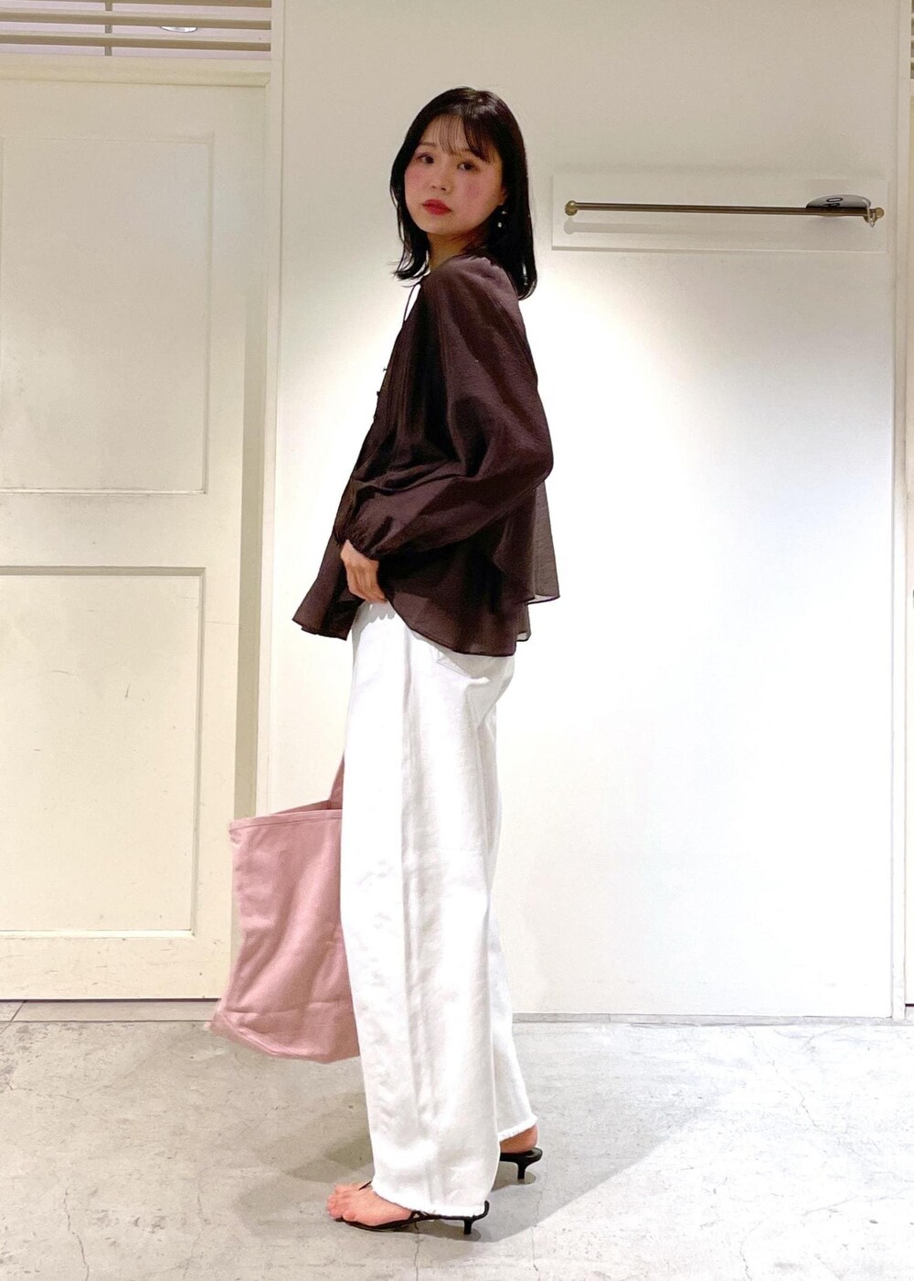 グレー系のタンクトップ、ブラック系のサンダル、ホワイト系のデニムパンツを着用したレディースの夏コーディネートの2枚目の写真