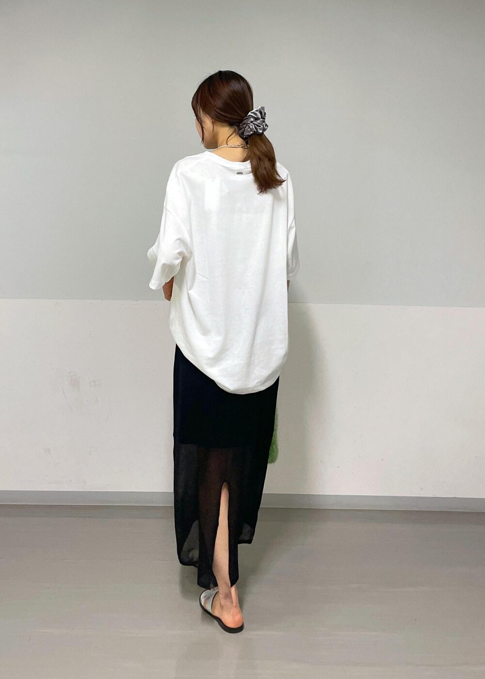 ブラック系のスカート、グリーン系のハンドバッグ、ホワイト系のTシャツ/カットソーを着用したレディースの夏コーディネートの3枚目の写真