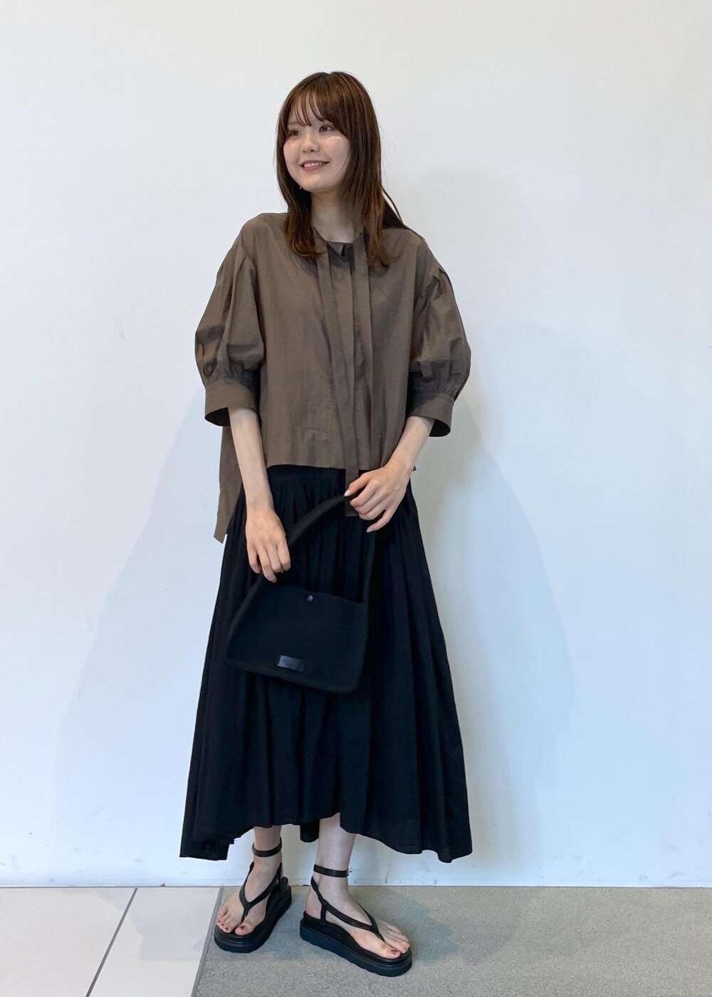 ブラック系のサンダル、ブラック系のスカート、ブラック系のハンドバッグを着用したレディースの夏コーディネートの2枚目の写真