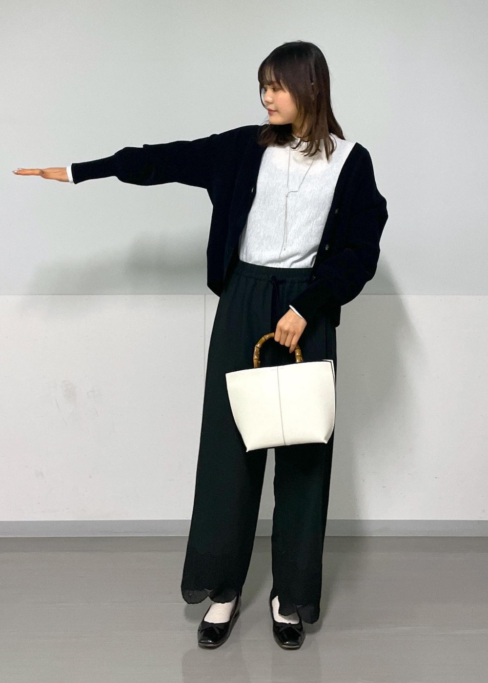 ブラック系のカーディガン/ボレロ、ホワイト系のTシャツ/カットソー、ホワイト系のハンドバッグを着用したレディースの冬コーディネートの5枚目の写真
