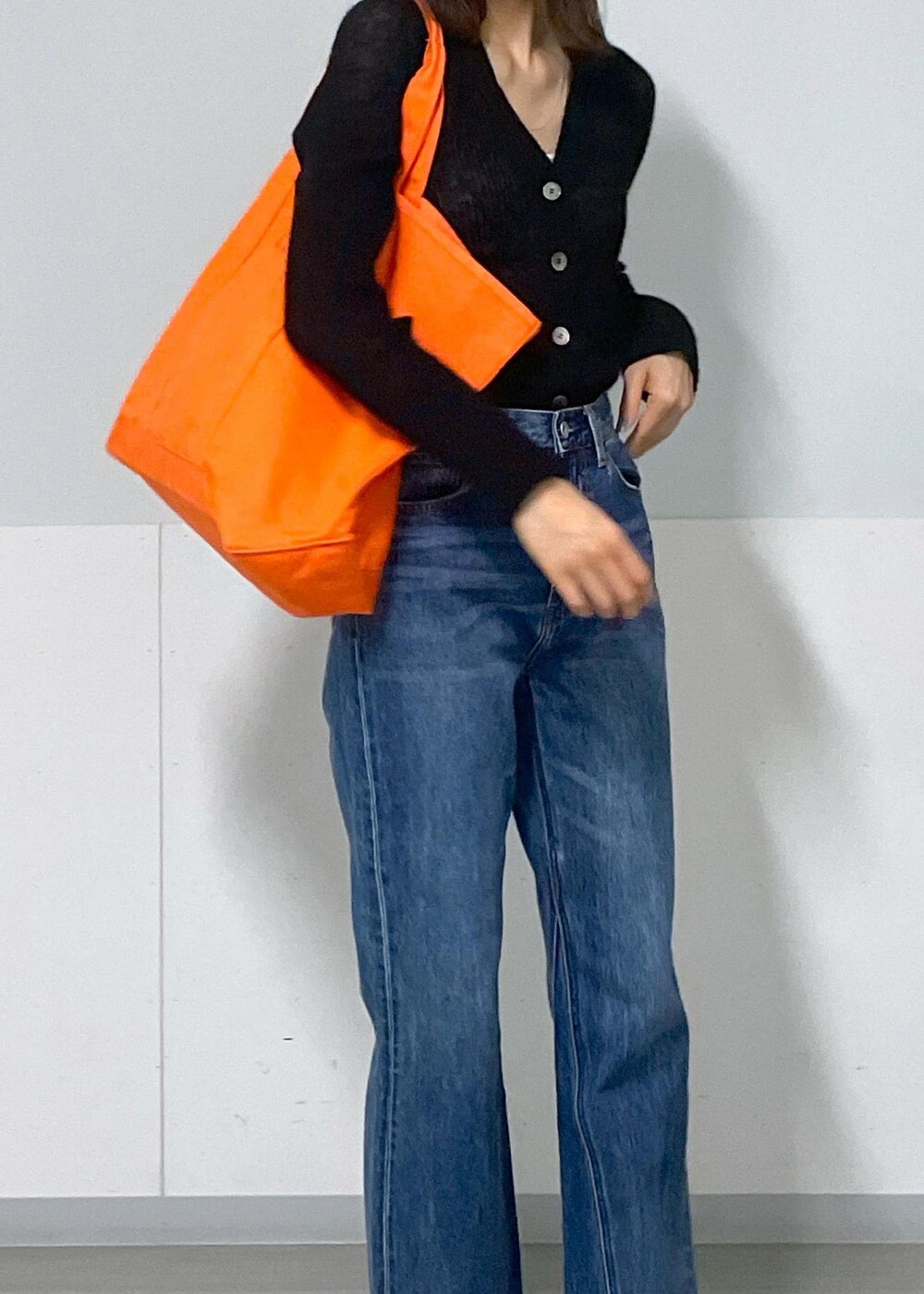 グレー系のタンクトップ、ブラック系のカーディガン/ボレロ、ブルー系のデニムパンツを着用したレディースの秋コーディネートの8枚目の写真