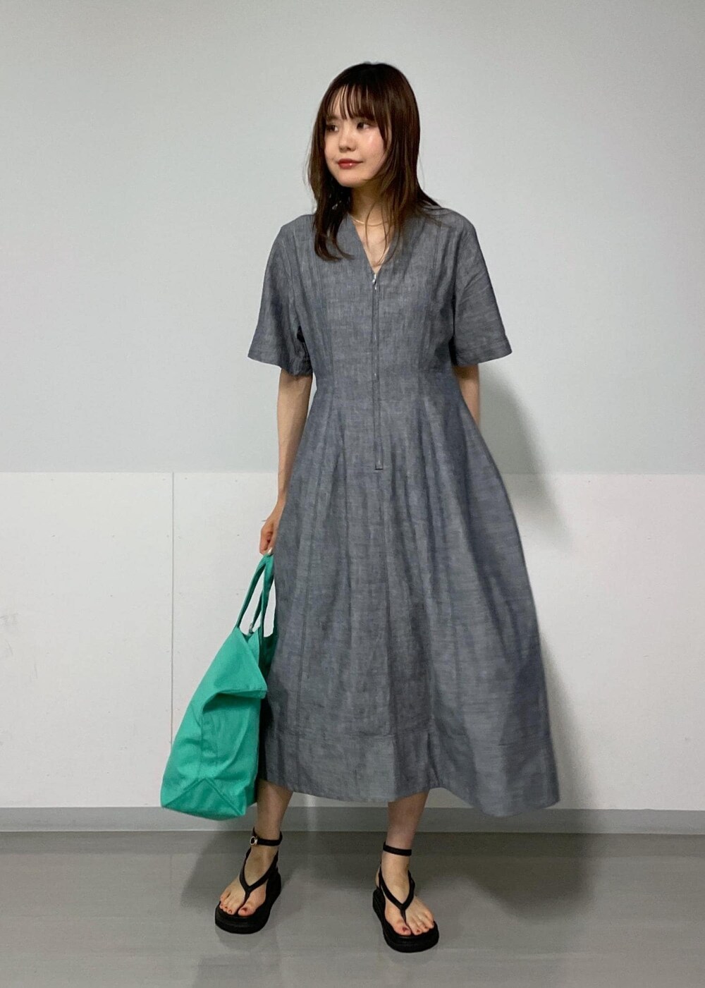 ブラック系のサンダル、ブルー系のワンピース、グリーン系のトートバッグを着用したレディースの夏コーディネートの2枚目の写真