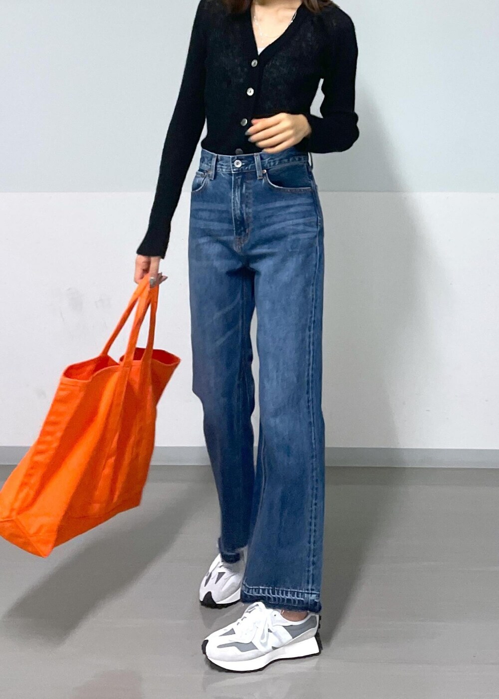 グレー系のタンクトップ、ブラック系のカーディガン/ボレロ、ブルー系のデニムパンツを着用したレディースの秋コーディネートの4枚目の写真