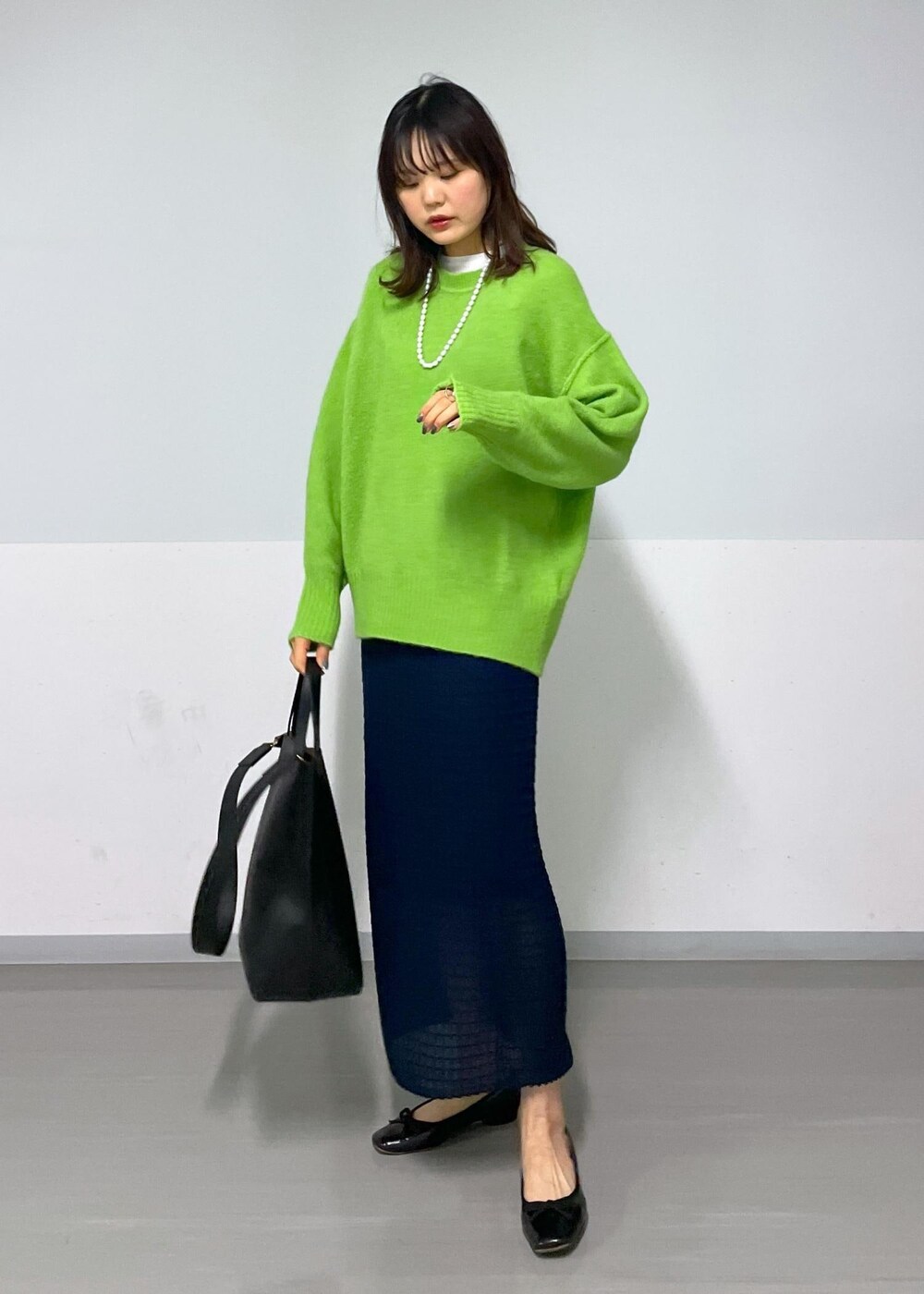 グリーン系のニット/セーター、ホワイト系のTシャツ/カットソー、ブラック系のトートバッグを着用したレディースの冬コーディネートの2枚目の写真