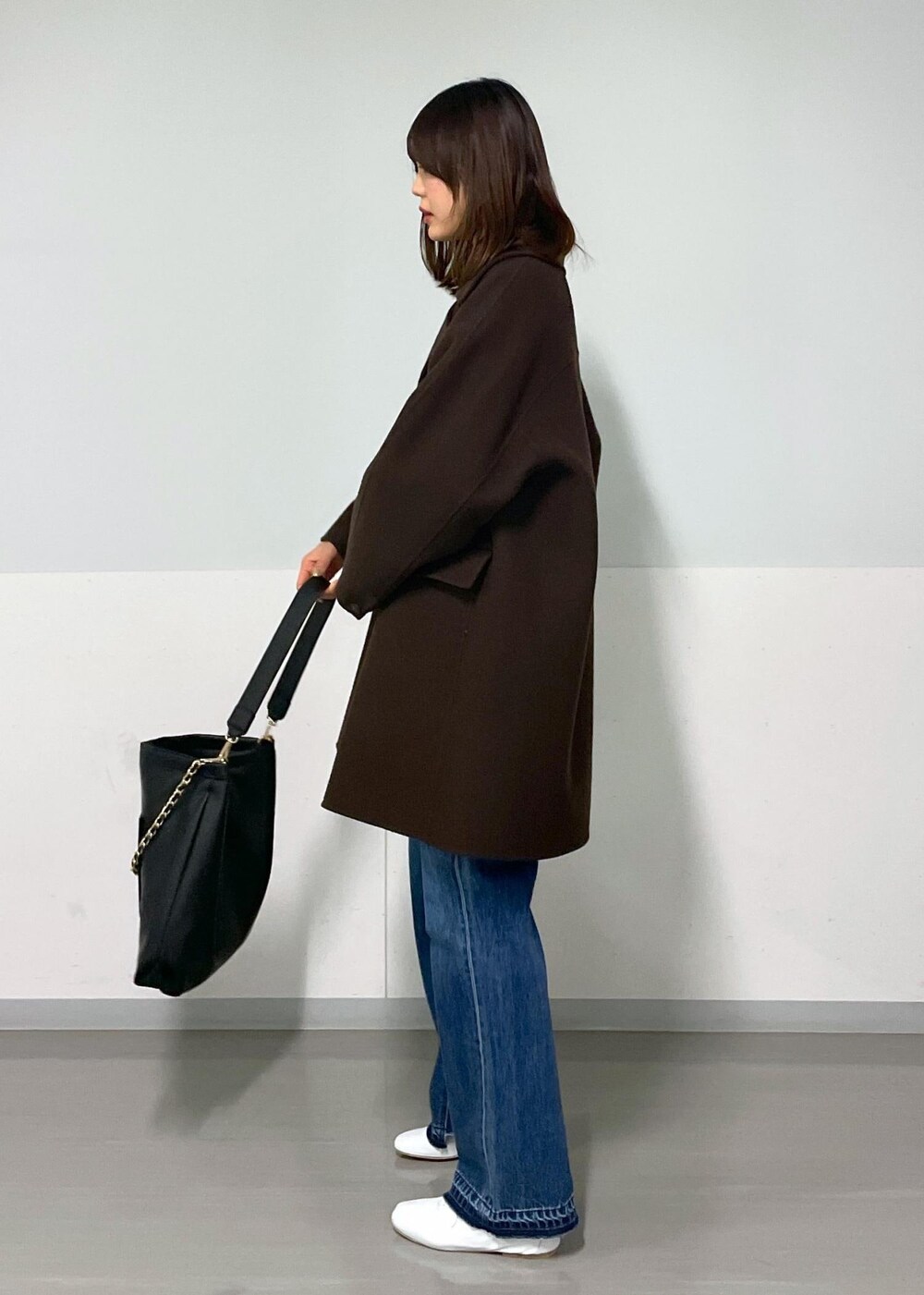 ブラウン系のピーコート、ブラック系のトートバッグ、ブラウン系のTシャツ/カットソーを着用したレディースの冬コーディネートの2枚目の写真