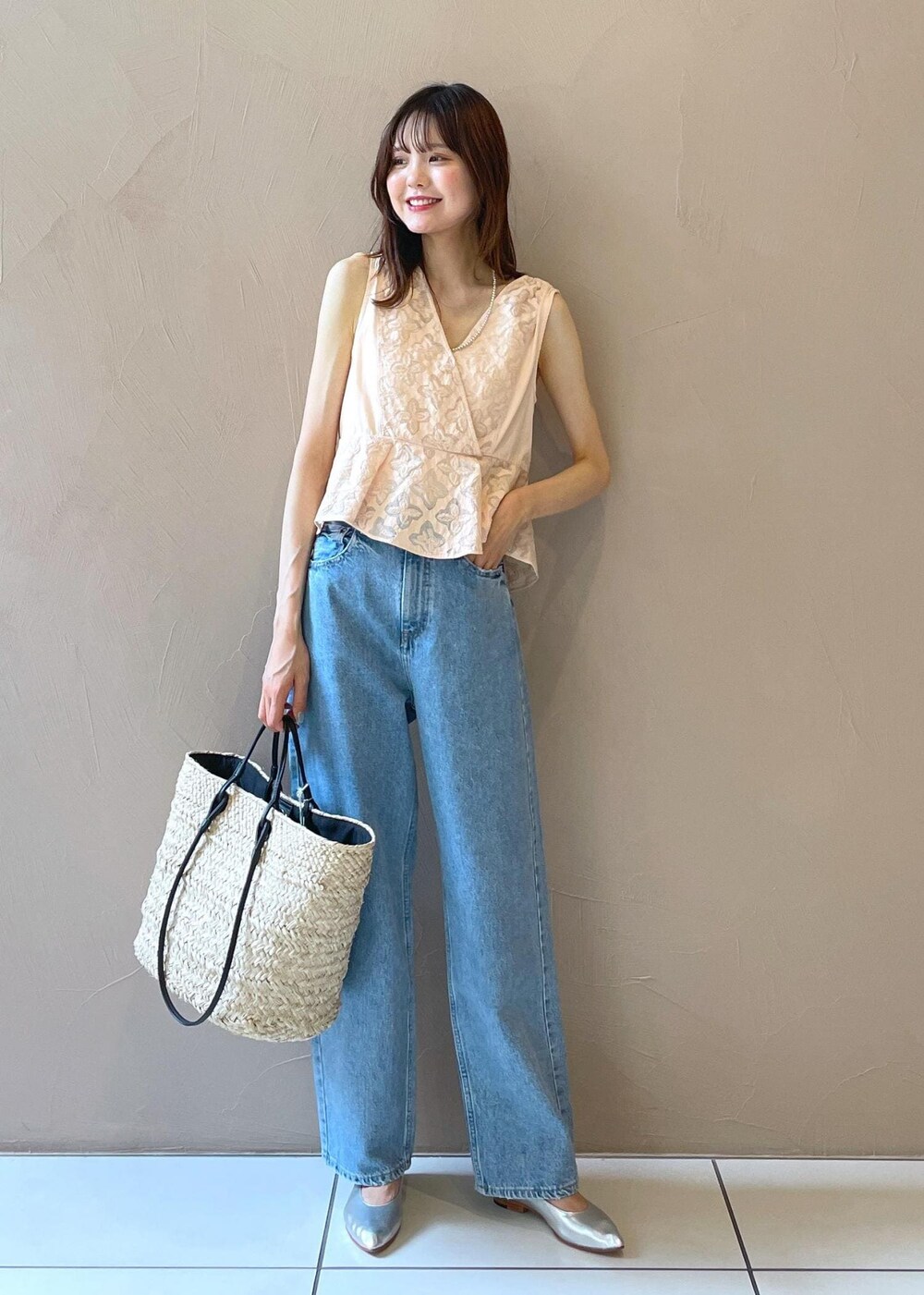 ホワイト系のかごバッグ、ブルー系のデニムパンツ、シルバー系のパンプスを着用したレディースの夏コーディネートの5枚目の写真