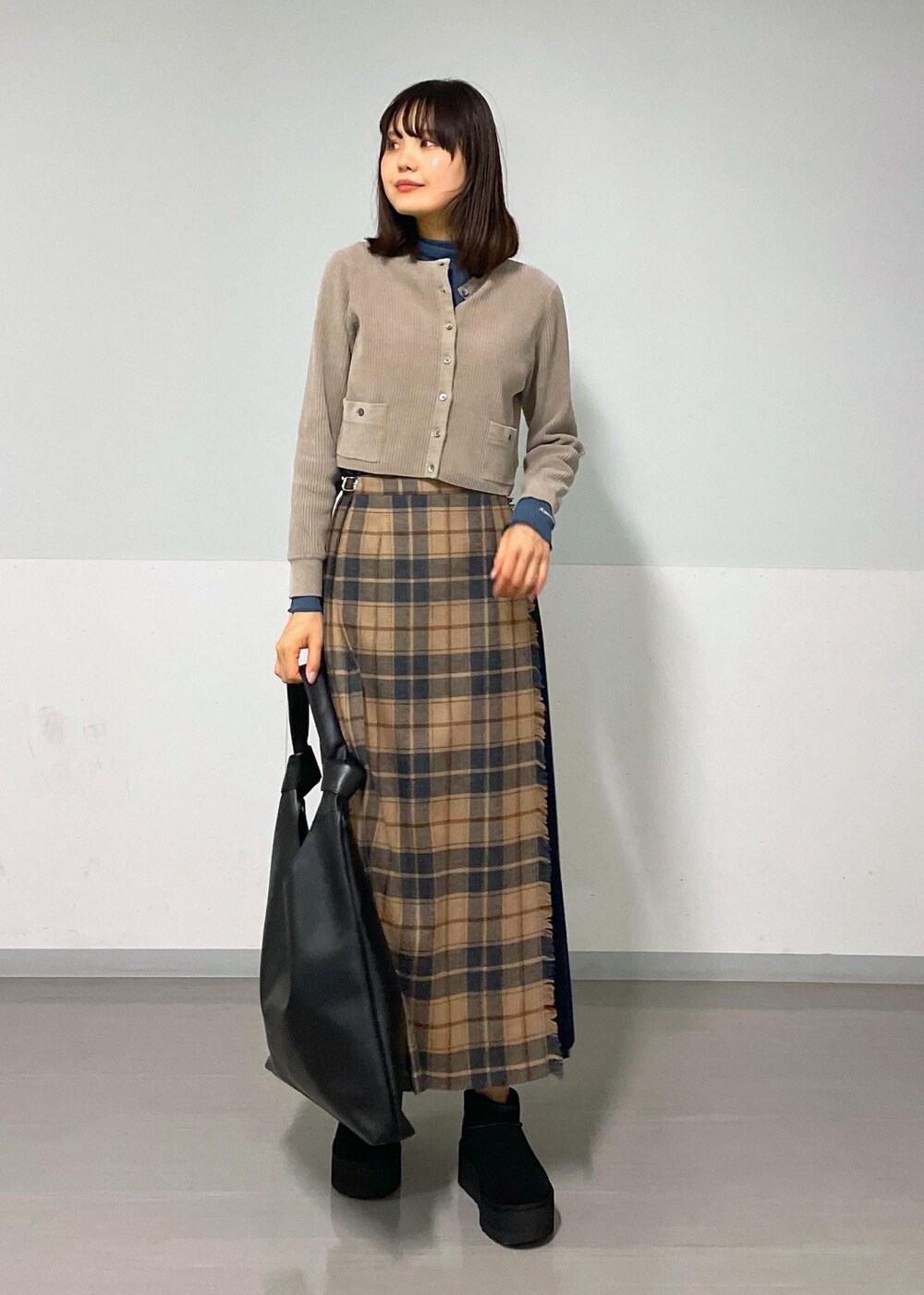 ブルー系のTシャツ/カットソー、ベージュ系のスカート、グレー系のカーディガン/ボレロを着用したレディースの秋コーディネートの4枚目の写真