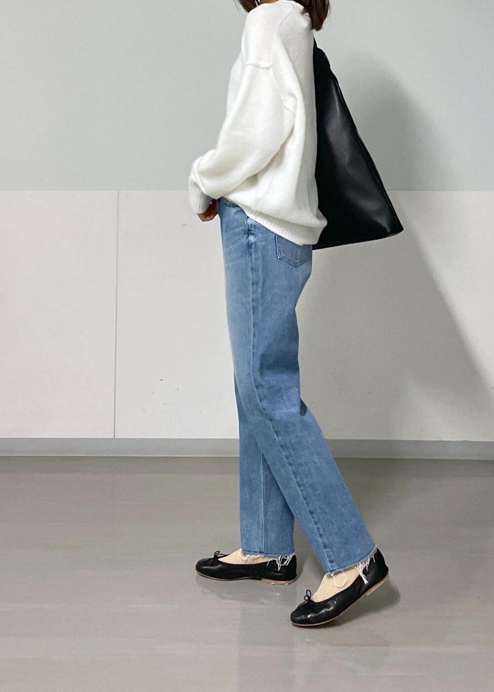 ブラック系のバレエシューズ、ブルー系のデニムパンツ、ホワイト系のニット/セーターを着用したレディースの秋コーディネートの4枚目の写真