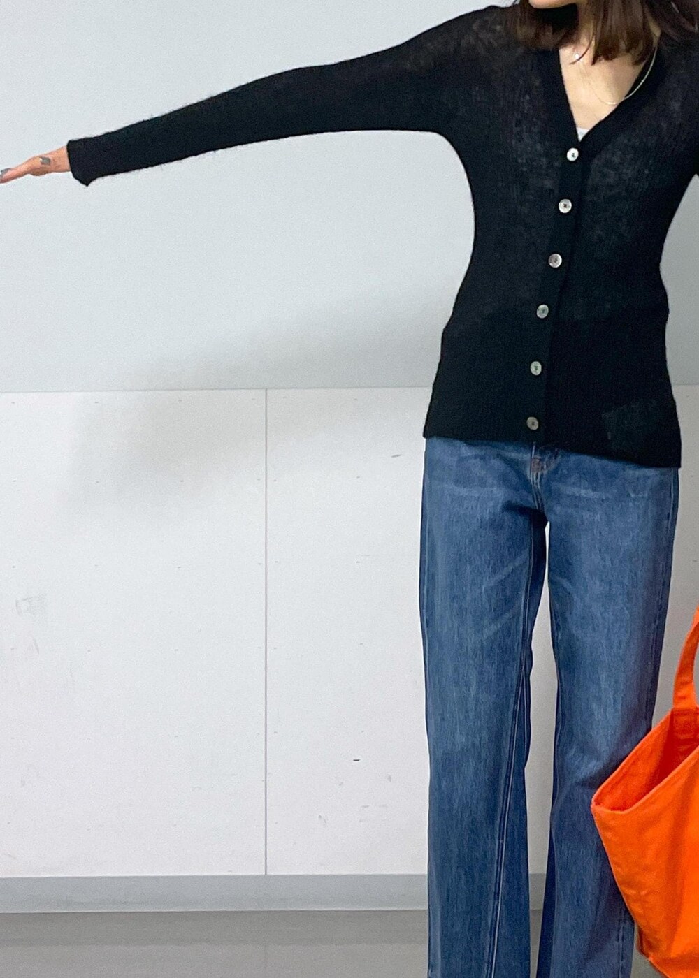 グレー系のタンクトップ、ブラック系のカーディガン/ボレロ、ブルー系のデニムパンツを着用したレディースの秋コーディネートの6枚目の写真