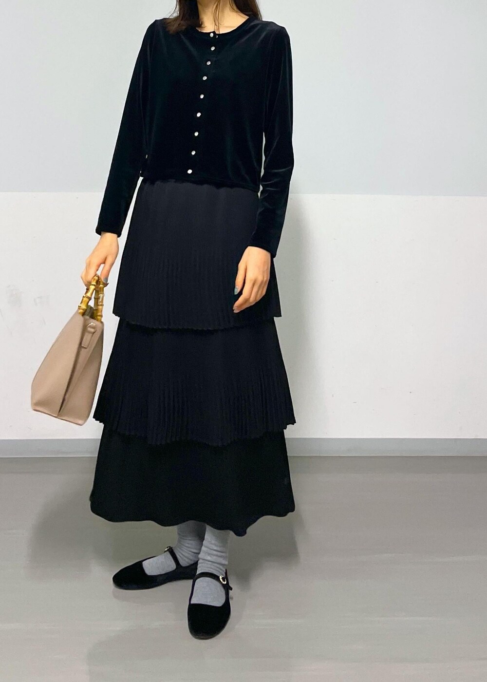 ブラック系のカーディガン/ボレロ、ブラック系のスカート、ベージュ系のハンドバッグを着用したレディースの冬コーディネートの5枚目の写真