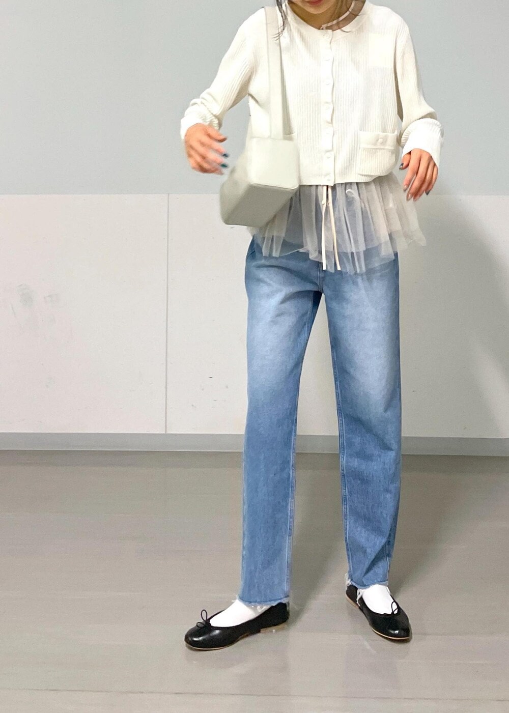 ブラック系のバレエシューズ、ホワイト系のカーディガン/ボレロ、ブルー系のデニムパンツを着用したレディースの秋コーディネートの3枚目の写真