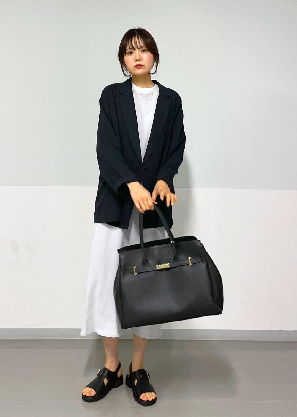 ブラック系のサンダル、グレー系のワンピース、ホワイト系のTシャツ/カットソーを着用したレディースの冬コーディネートの2枚目の写真