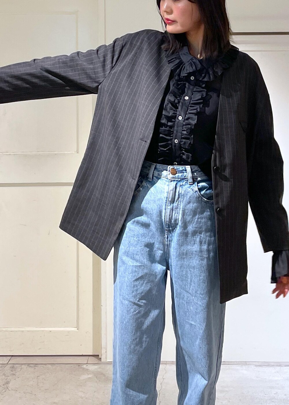 グレー系のノーカラージャケット、ブルー系のデニムパンツ、ブラック系のボストンバッグを着用したレディースの夏コーディネートの4枚目の写真