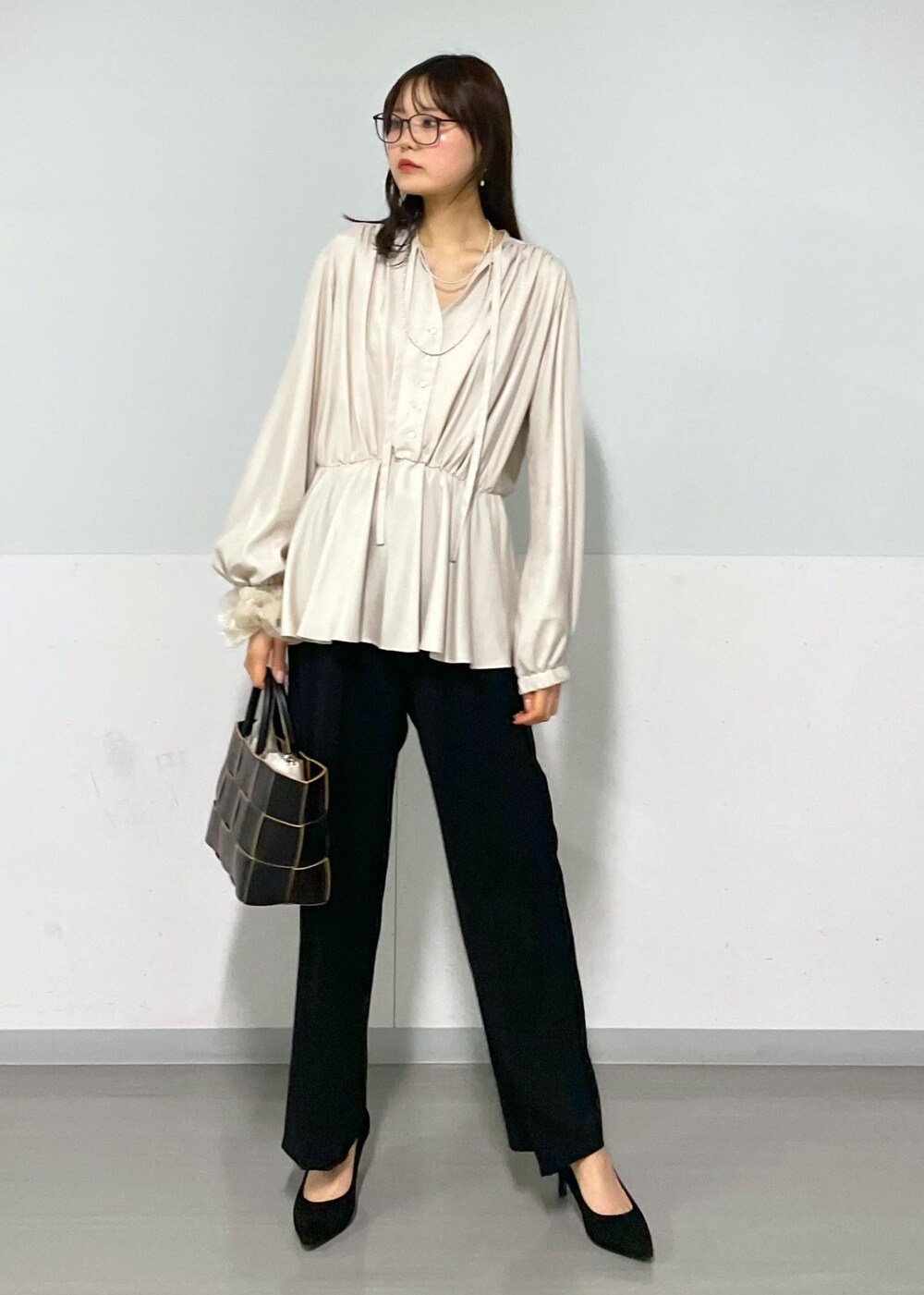 ブラック系のトートバッグ、ブラック系のスラックス、ベージュ系のシャツ/ブラウスを着用したレディースの春コーディネートの5枚目の写真