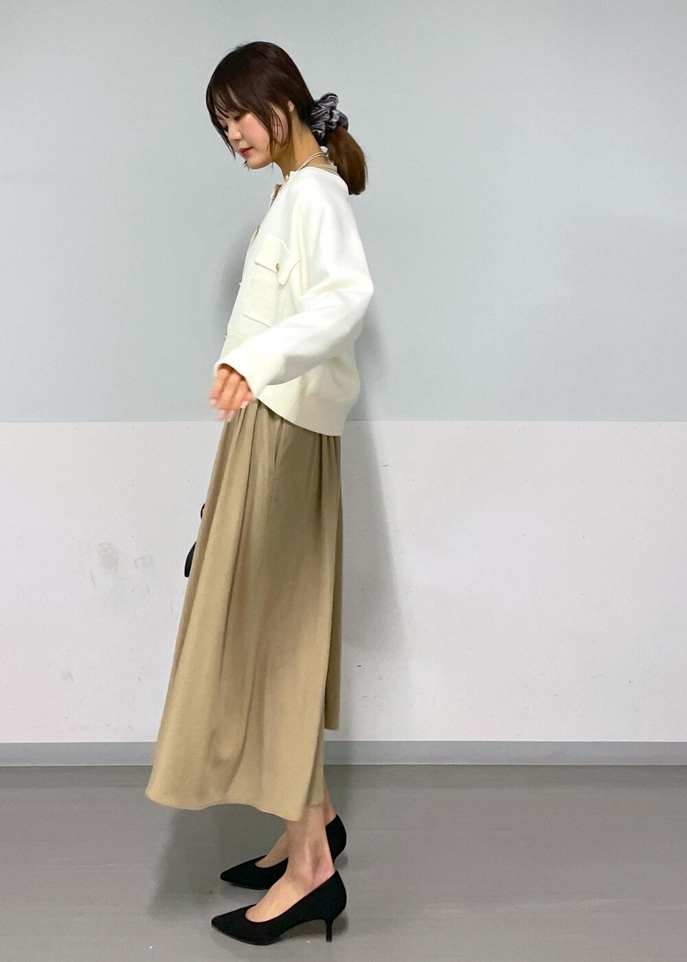 ブラック系のショルダーバッグ、ベージュ系のワンピース、ホワイト系のカーディガン/ボレロを着用したレディースの春コーディネートの4枚目の写真