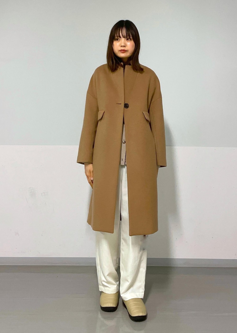 ブラック系のショルダーバッグ、イエロー系のチェスターコート、ベージュ系のカーディガン/ボレロを着用したレディースの冬コーディネートの5枚目の写真