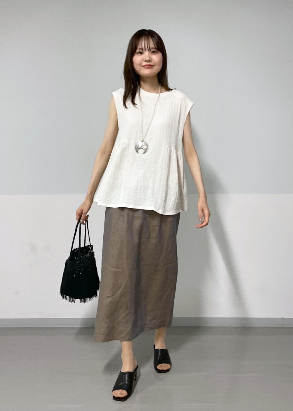 ホワイト系のTシャツ/カットソー、ブラック系のサンダル、ブラック系のトートバッグを着用したレディースの夏コーディネートの3枚目の写真