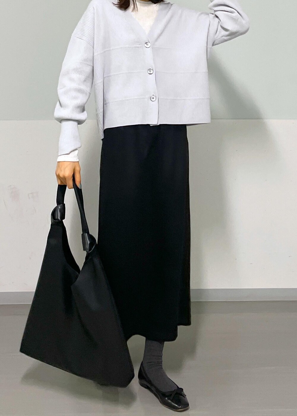 ブラック系のトートバッグ、ホワイト系のTシャツ/カットソー、グレー系のカーディガン/ボレロを着用したレディースの冬コーディネートの6枚目の写真