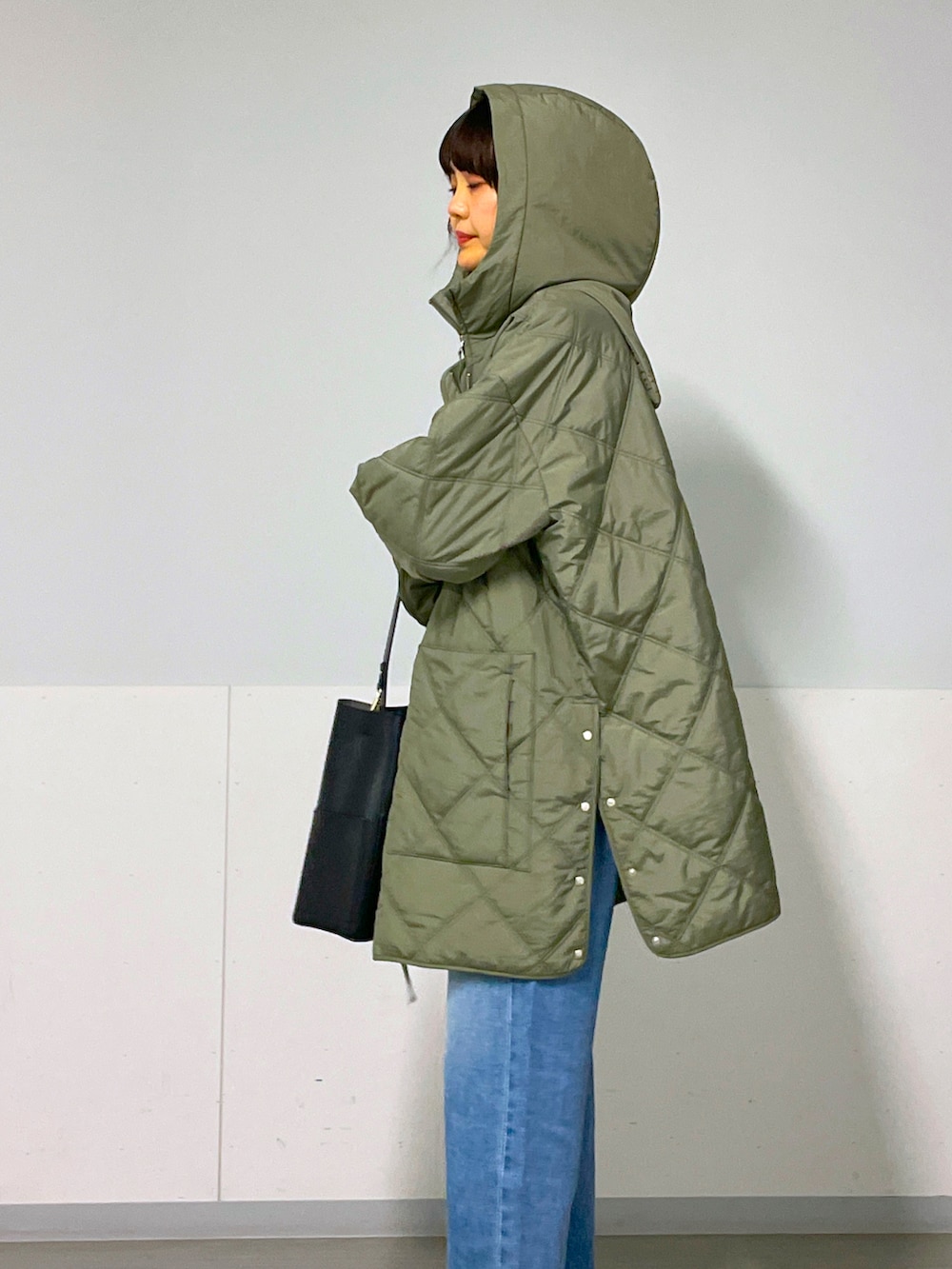 グリーン系のブルゾン、ブルー系のデニムパンツ、ブラック系のバレエシューズを着用したレディースの秋コーディネートの4枚目の写真