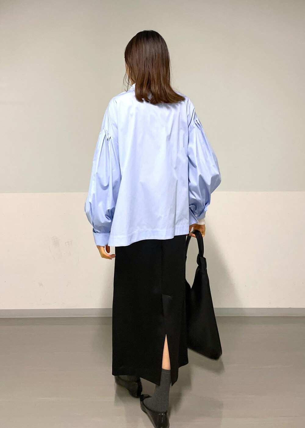 ブルー系のシャツ/ブラウス、ブラック系のトートバッグ、ブラック系のスカートを着用したレディースの冬コーディネートの2枚目の写真