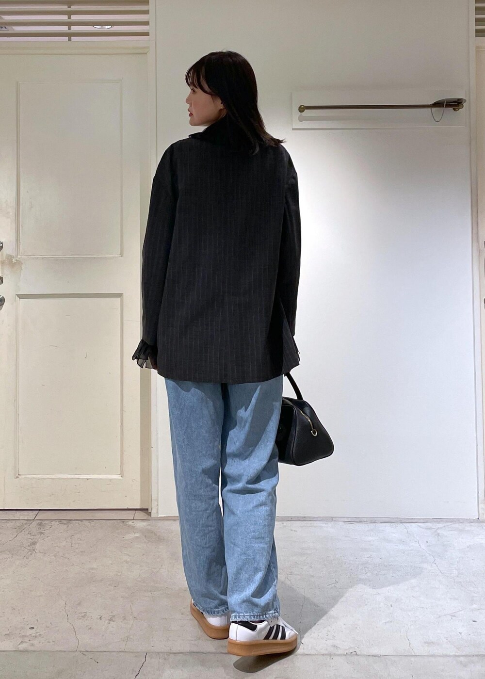 グレー系のノーカラージャケット、ブルー系のデニムパンツ、ブラック系のボストンバッグを着用したレディースの夏コーディネートの5枚目の写真