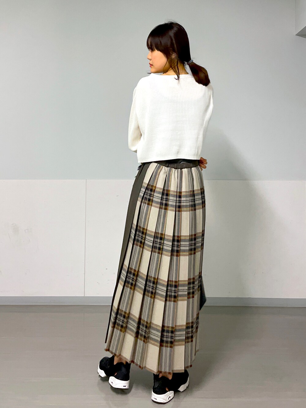 ホワイト系のカーディガン/ボレロ、イエロー系のスカート、ベージュ系のスニーカーを着用したレディースの秋コーディネートの2枚目の写真