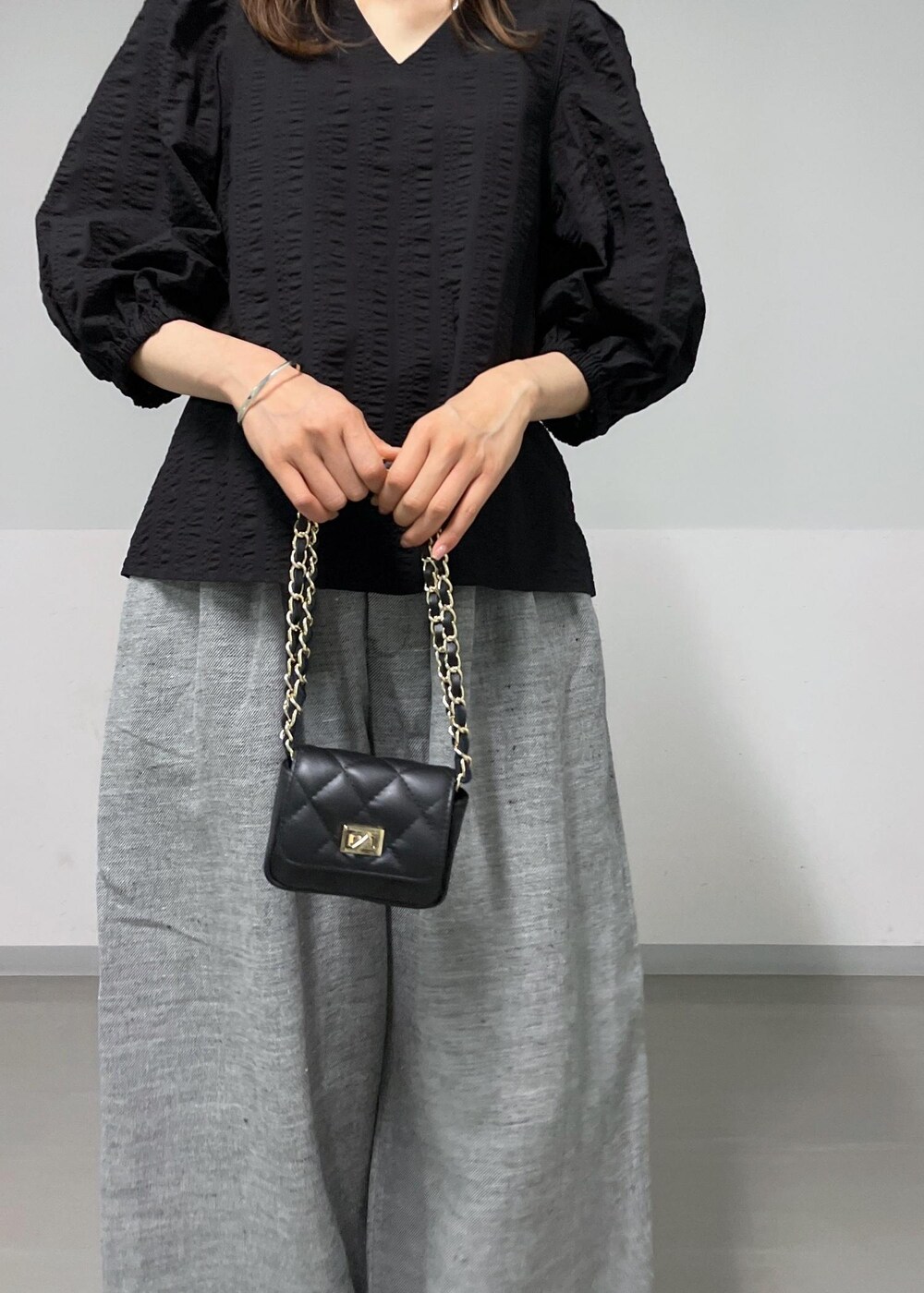 ブラック系のショルダーバッグ、グレー系のスラックス、ブラック系のシャツ/ブラウスを着用したレディースの夏コーディネートの7枚目の写真