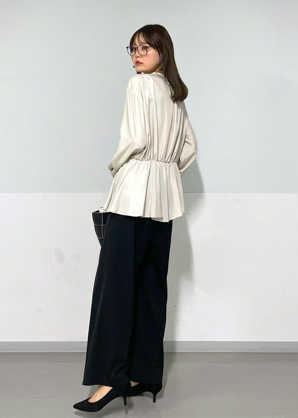 ブラック系のトートバッグ、ブラック系のスラックス、ベージュ系のシャツ/ブラウスを着用したレディースの春コーディネートの3枚目の写真