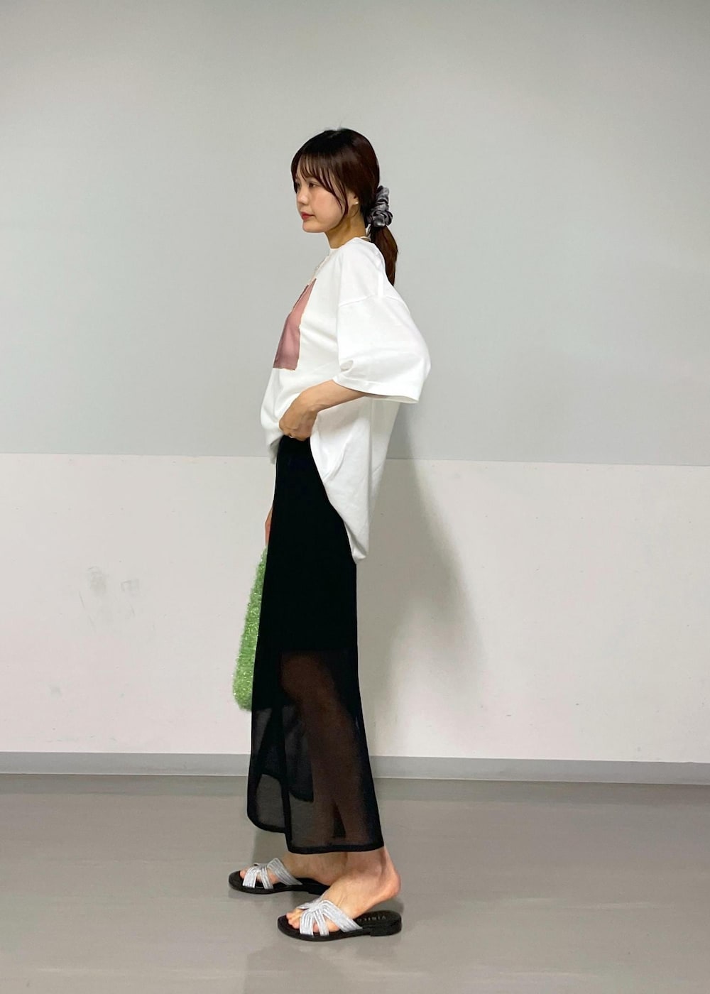 ブラック系のスカート、グリーン系のハンドバッグ、ホワイト系のTシャツ/カットソーを着用したレディースの夏コーディネートの2枚目の写真