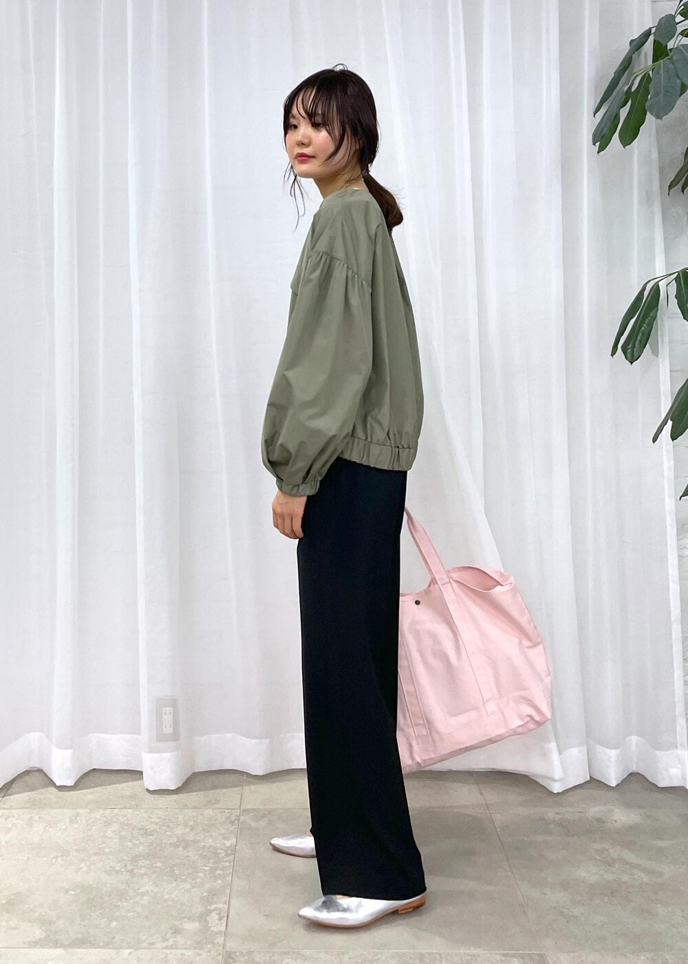 ブラック系のスラックス、グリーン系のブルゾン、シルバー系のパンプスを着用したレディースの冬コーディネートの3枚目の写真