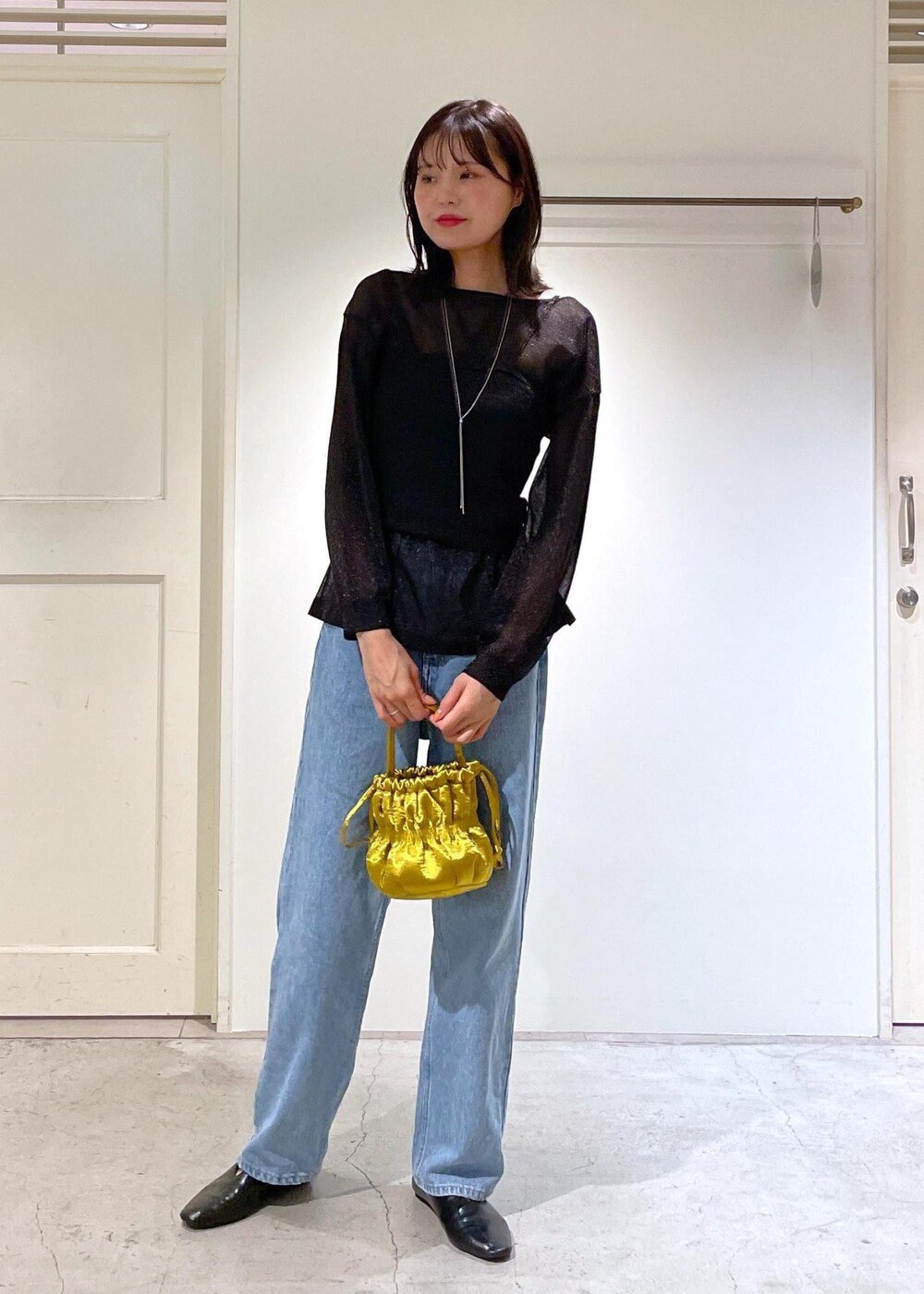 イエロー系のショルダーバッグ、ブルー系のデニムパンツ、ブラック系のTシャツ/カットソーを着用したレディースの夏コーディネートの3枚目の写真