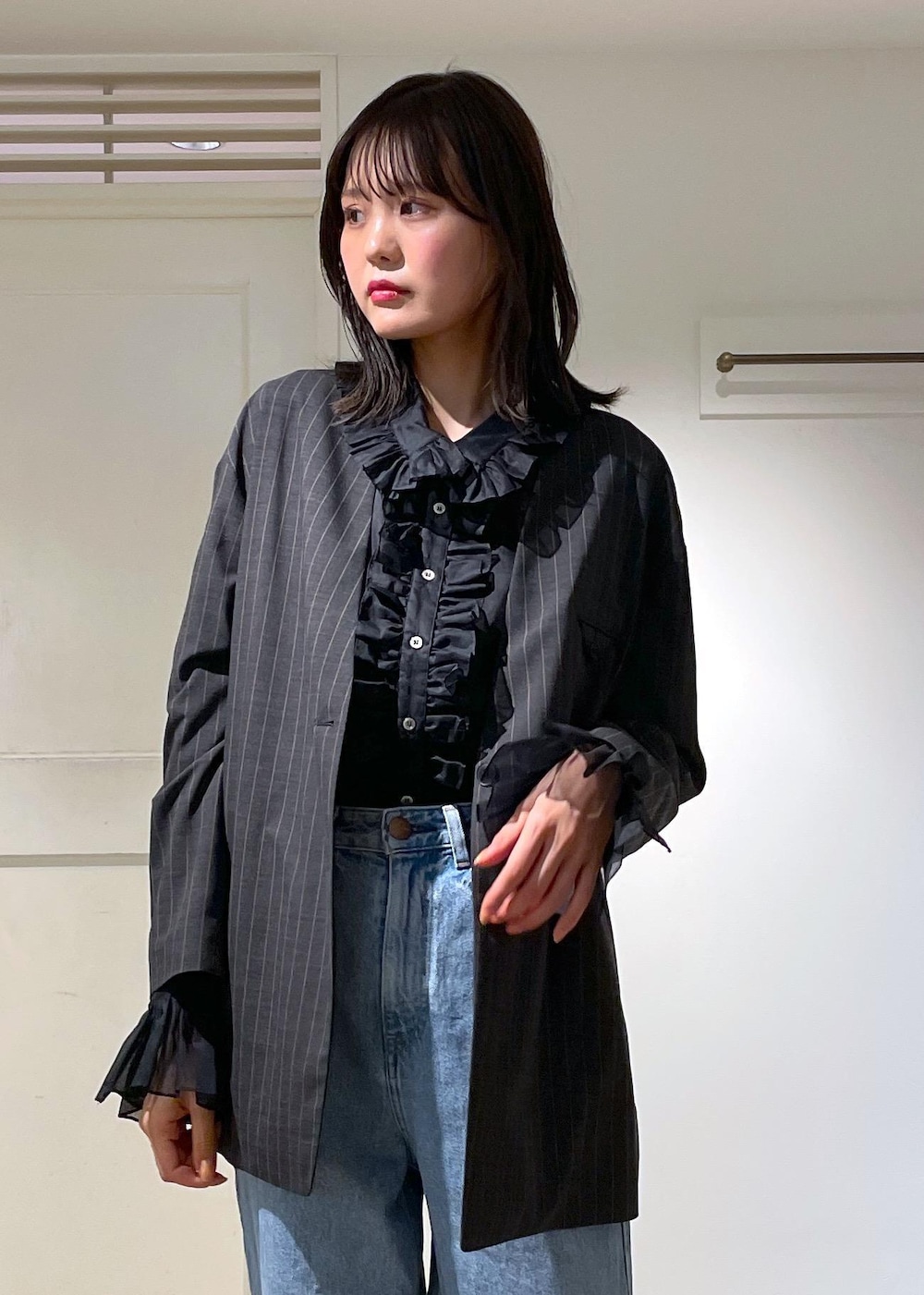 グレー系のノーカラージャケット、ブルー系のデニムパンツ、ブラック系のボストンバッグを着用したレディースの夏コーディネートの3枚目の写真