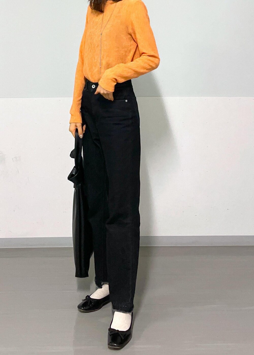 ブラック系のトートバッグ、グレー系のデニムパンツ、オレンジ系のTシャツ/カットソーを着用したレディースの冬コーディネートの8枚目の写真