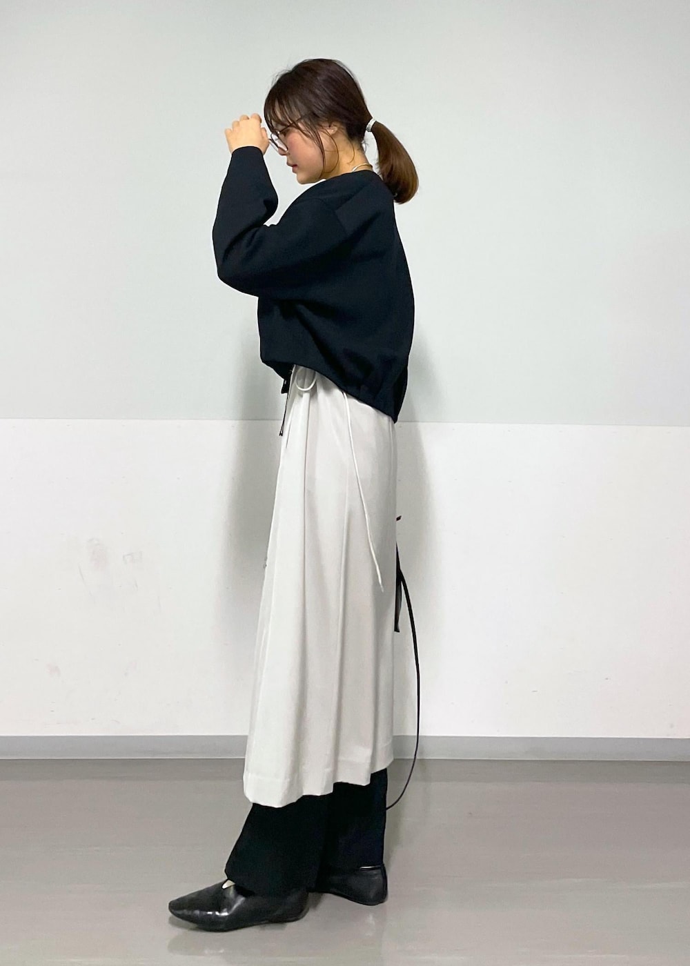 ベージュ系のジャンパースカート、ブラック系のブルゾン、ブラック系のスラックスを着用したレディースの春コーディネートの4枚目の写真