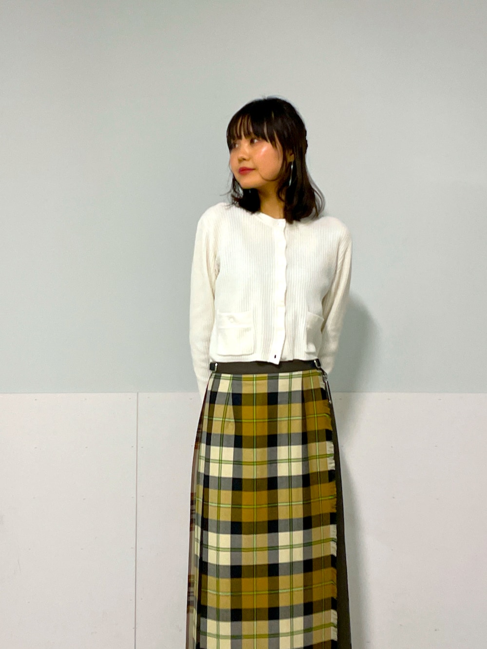 ホワイト系のカーディガン/ボレロ、イエロー系のスカート、ブラック系のシューズを着用したレディースの冬コーディネートの5枚目の写真