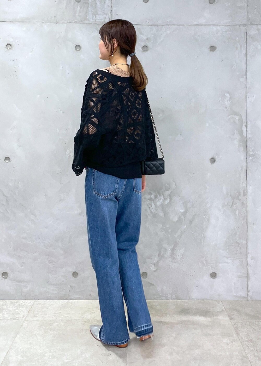 ブラック系のショルダーバッグ、ブルー系のデニムパンツ、ゴールド系のベストを着用したレディースの春コーディネートの5枚目の写真