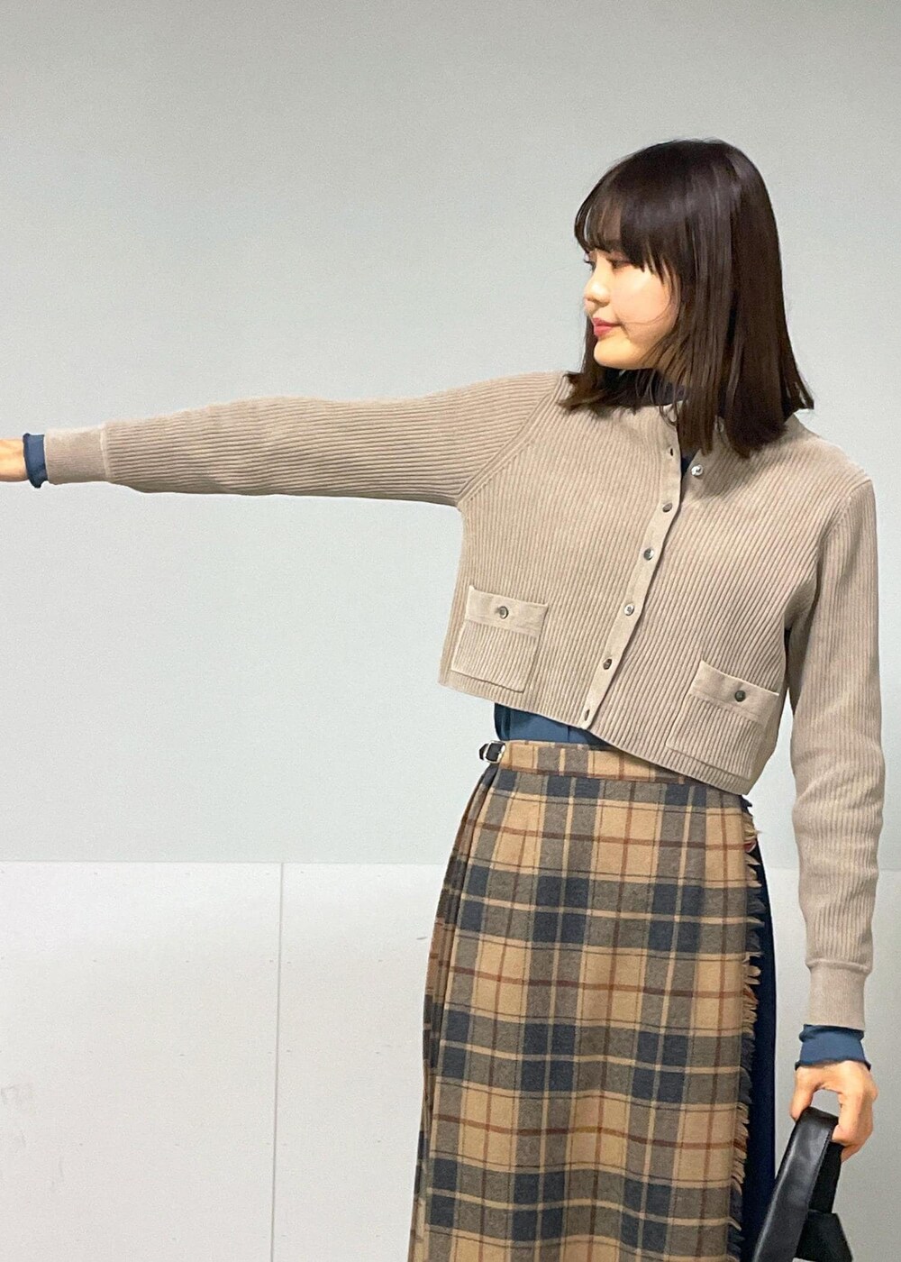 ブルー系のTシャツ/カットソー、ベージュ系のスカート、グレー系のカーディガン/ボレロを着用したレディースの秋コーディネートの7枚目の写真