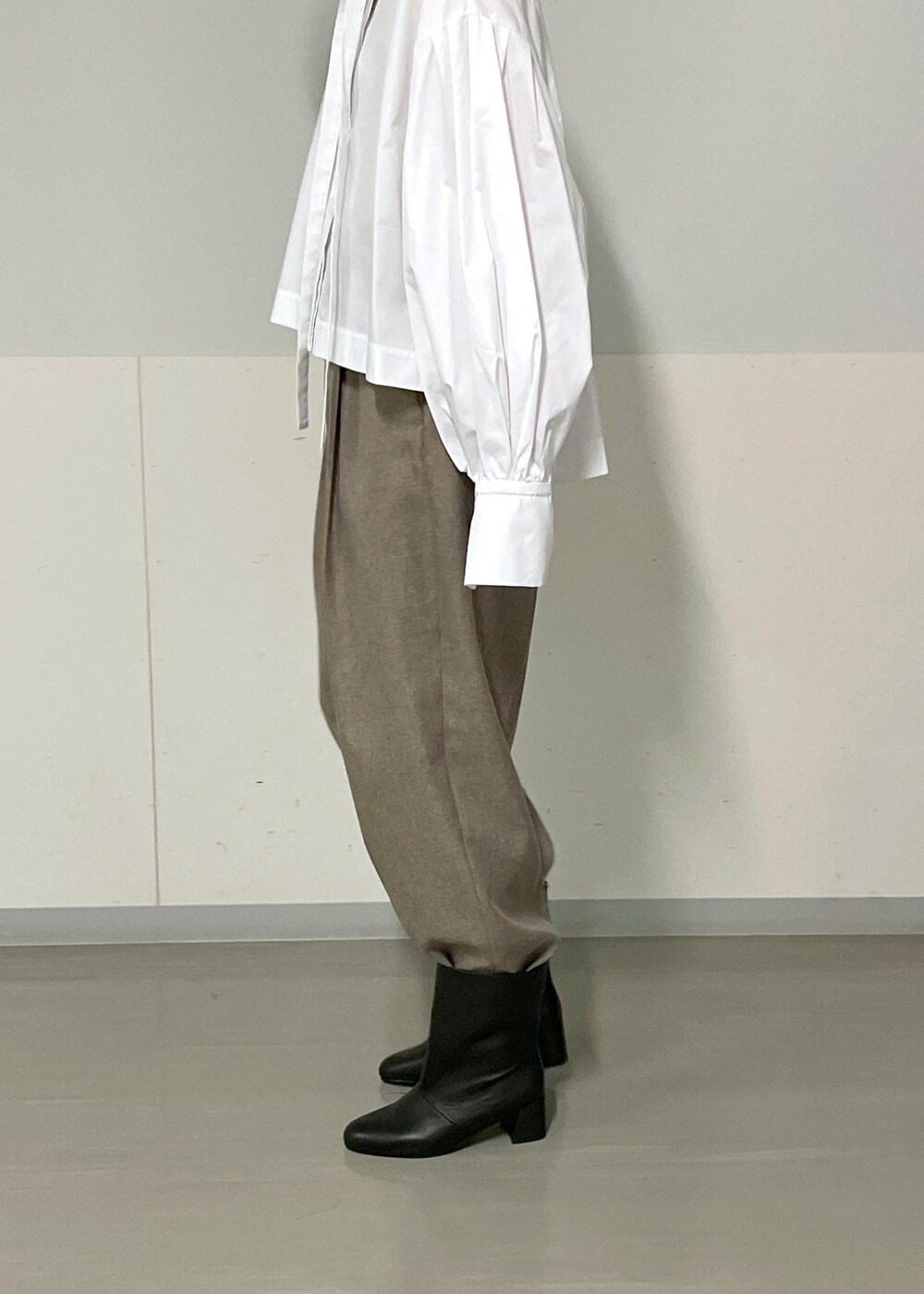 ベージュ系のスラックス、ベージュ系のジャンパースカート、ホワイト系のシャツ/ブラウスを着用したレディースの秋コーディネートの9枚目の写真